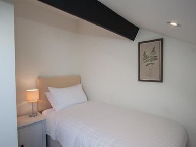 A bedroom with a single bed a bedside table with lamp and framed botanical print on wall at Robins Nest in Coniston