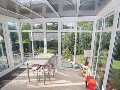 A conservatory with a table and four chairs and a lamp on a small table at Brimbles in Keswick