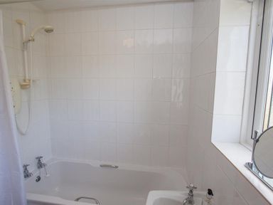 A bathroom with a bathtub shower combination and a sink near a window at Brimbles in Keswick