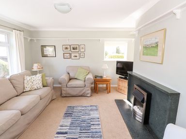 A living room with a sofa armchair rug fireplace and television at Brimbles in Keswick