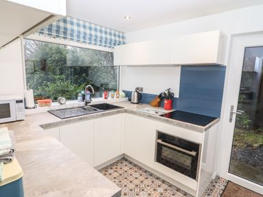 A kitchen with a large window over the sink electric stove oven and a door to the outside at Helm Crag in Grasmere