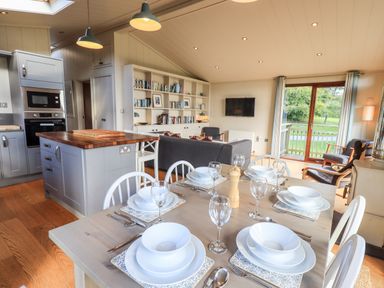 A dining table set with plates glasses and utensils in a kitchen and living room area at How Beck in Hawkshead