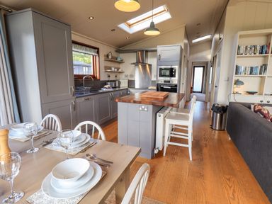 A kitchen and dining area with grey cabinets wooden floors dining table set for four and a sofa at How Beck in Hawkshead