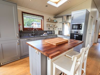 A kitchen with grey cabinets a wooden island with stools and appliances at How Beck in Hawkshead