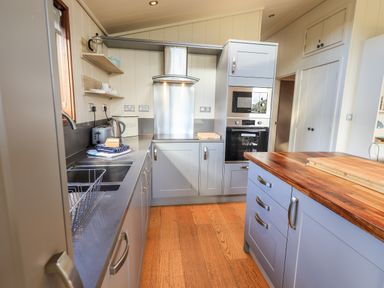 A kitchen with blue cabinets wooden floor metal sink toaster and built in oven at How Beck in Hawkshead