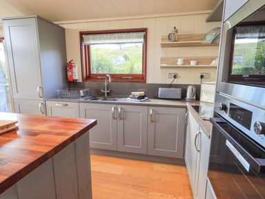A kitchen with gray cabinets a wooden countertop a window and appliances at How Beck in Hawkshead