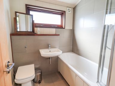 A bathroom with a bathtub a sink a toilet a mirror and a window at How Beck in Hawkshead