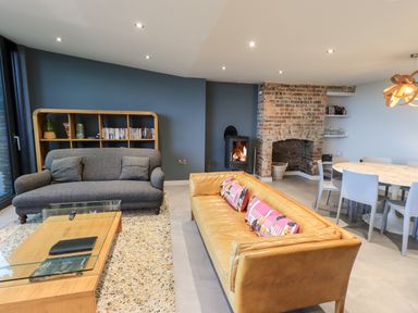 A living room with two sofas a wooden bookshelf a glass top coffee table a brick fireplace and a dining table with chairs at Gillside Millbeck