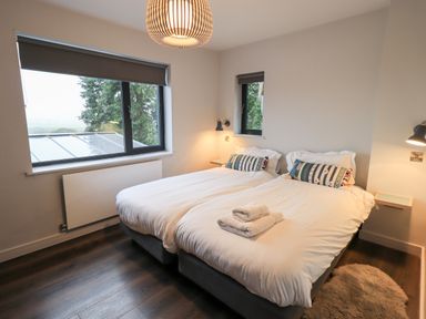 A bedroom with two single beds pushed together with white bedding and towels on top at Gillside in Millbeck