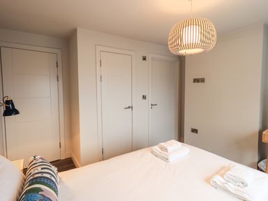 A bedroom with a bed and folded towels on it three white doors and a hanging ceiling light at Gillside in Millbeck