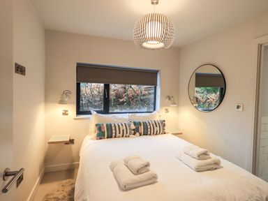 A bedroom with a double bed folded towels on the bed a round mirror and a window with a blind at Gillside in Millbeck