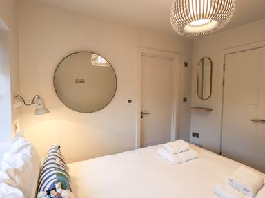 A bedroom with a bed folded towels round mirror wall lamp and two doors at Gillside in Millbeck