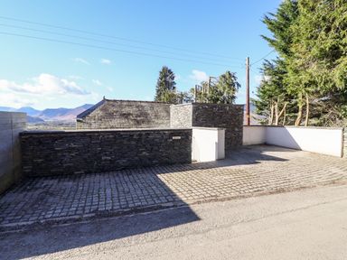 An outdoor area with stone walls and a cobblestone ground next to a road at Gillside in Millbeck