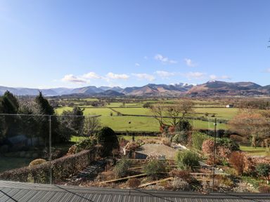 A garden with various shrubs and hedges with fields and mountains in the background at Gillside in Millbeck