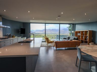 An open plan kitchen and living area with a kitchen island a sofa and a large window with mountain views at Gillside in Millbeck