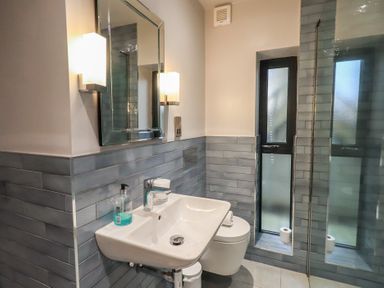 A bathroom with a sink mirror wall lights toilet and frosted windows at Gillside in Millbeck