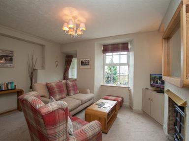 A living room with a sofa armchair coffee table and television at Swallow's Nest in Windermere
