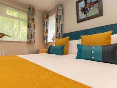 A bedroom with a bed with yellow and blue cushions and a yellow throw at Silver Howe in Grasmere