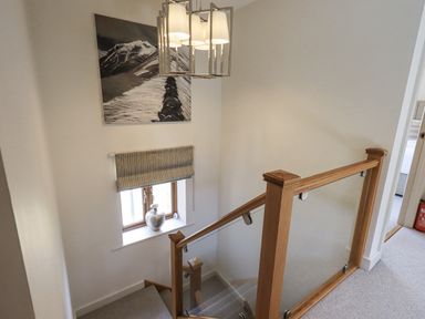 A staircase with a hanging light and a window in the hallway at No 7 Ambleside