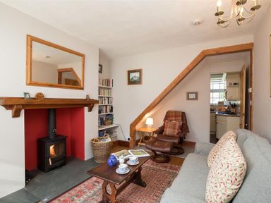 A living room with a fireplace a wood stove a gray sofa and a brown recliner at Briardale Cottage in Ambleside