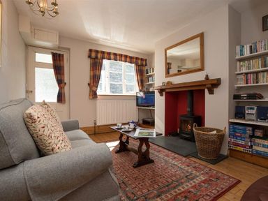 A living room with a gray sofa a wooden coffee table a fireplace and bookshelves at Briardale Cottage Ambleside