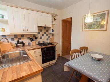 A kitchen with wooden countertops a sink a gas stove and a dining table with polka dot tablecloth at Briardale Cottage in Ambleside
