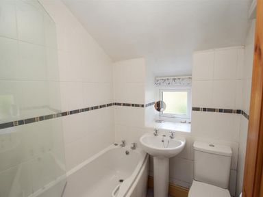 A bathroom with a bathtub sink toilet and a window at Briardale Cottage in Ambleside