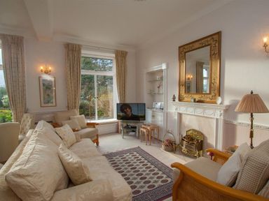 A living room with sofas a fireplace a mirror and a television at Betamere in Ambleside