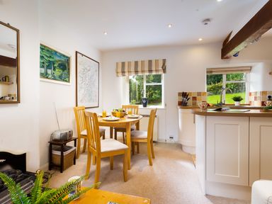 A dining area with wooden table and chairs next to a kitchen with countertop and sink at The Hayloft in Ambleside