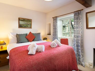 A bedroom with a bed covered in a red blanket and white towels on it at The Hayloft in Ambleside