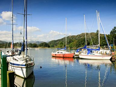 Sailboats docked on a lake with hills and trees in the background at The Hayloft in Ambleside