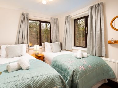 A bedroom with two single beds beside a window with curtains at Falls View Cottage in Ambleside