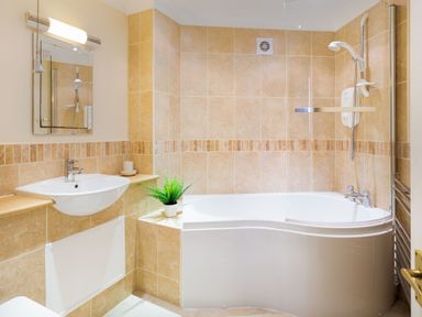 A bathroom with a bathtub and shower a wall-mounted sink and a mirror at Falls View Cottage in Ambleside