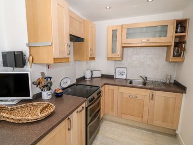A kitchen with wooden cabinets and a stove next to a sink at Bryn Mor in Church Bay