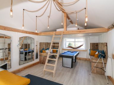 A game room with a pool table a telescope wooden ladder and seating areas with cushions at Bryn Mor in Church Bay
