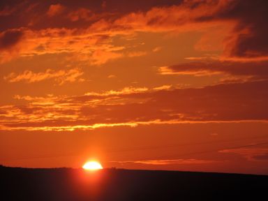 A sunset with the sun partially below the horizon and clouds in the sky
