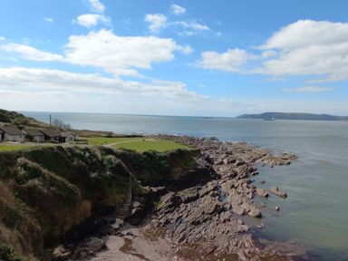 A rocky coastline with houses on grassy land and stairs leading down to the shore at SoundView in Down Thomas