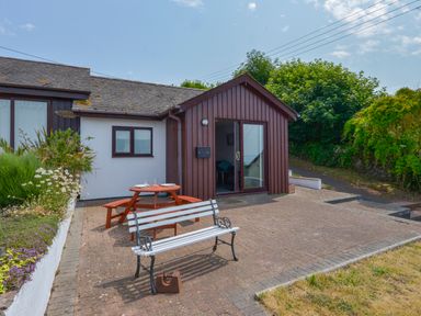 A patio area with a picnic table and a bench outside a single-story building at SoundView in Down Thomas