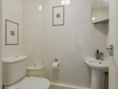 A bathroom with a toilet a sink and tiled walls at SoundView in Down Thomas