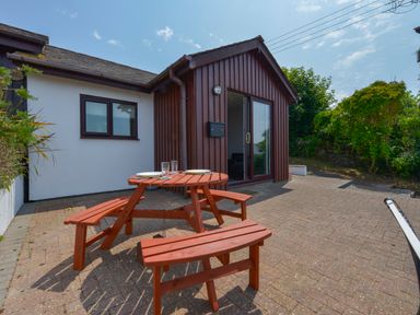 An outdoor patio area with a wooden picnic table and benches outside a house at SoundView in Down Thomas