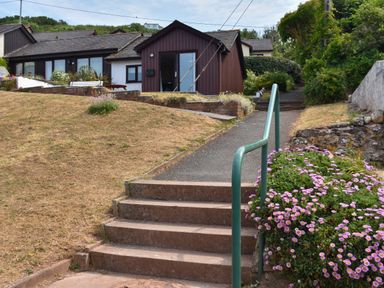 A pathway with stairs and green railing leading to brown and white houses with flower bushes at SoundView in Down Thomas