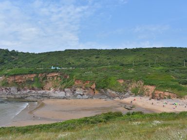 A beach with people on sand and a green hillside at SoundView in Down Thomas