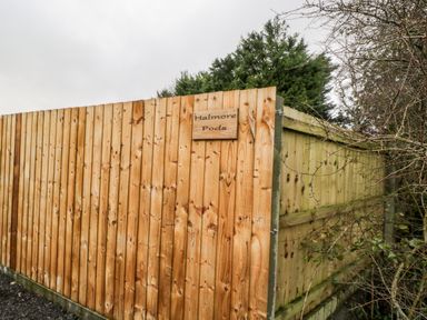 A wooden fence with a sign that reads Halmore Pods surrounded by trees at Halmore Pod Halmore near Berkeley