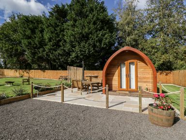 A wooden pod with a patio and outdoor furniture surrounded by a fenced garden at Halmore Pod in Halmore near Berkeley