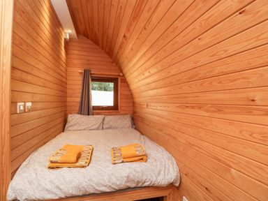 A bedroom with wooden walls a bed with pillows and folded towels near a window with a curtain at Halmore Pod Halmore near Berkeley