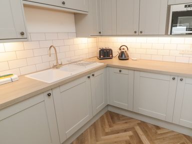 A kitchen corner with a sink toaster kettle and white cabinets at Through The Porthole in Falmouth