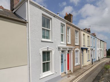 A street view of a row of terraced houses with various colored doors and windows at Through The Porthole in Falmouth