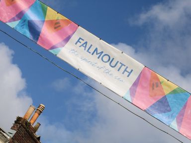 A colorful banner with the text Falmouth the spirit of the sea hanging above a brick chimney against a blue sky
