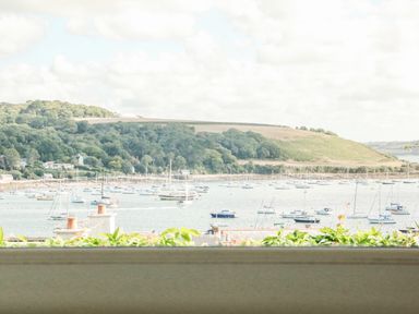 A view of boats on water with trees and hills in the background at Through The Porthole in Falmouth