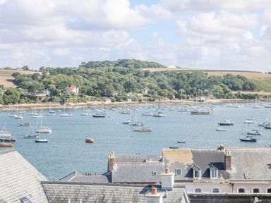 A harbor with many sailboats on the water and trees on a hill in the background at Through The Porthole in Falmouth